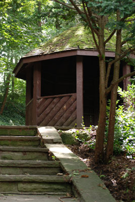 a wooden gazebo at the top of some stone stairs among the trees in Edwards Gardens
