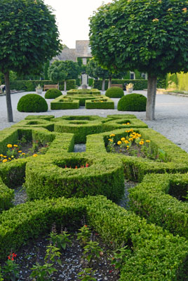 a formal garden area with low hedges and pruned trees