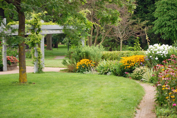 a long bed of perinnials curves towards the pergola